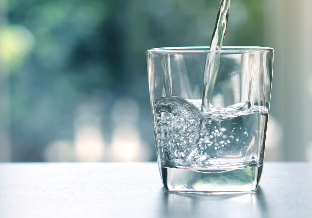 Close up the pouring purified fresh drink water from the bottle on table in living room