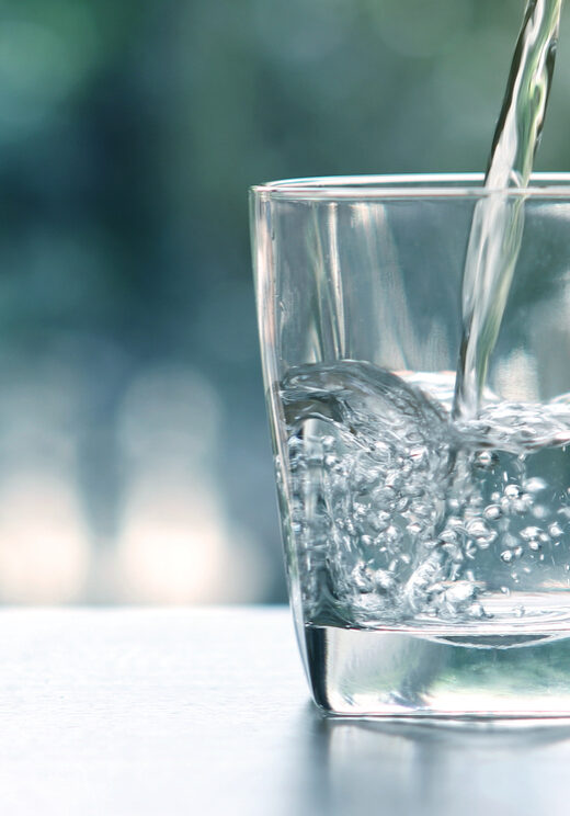 Close up the pouring purified fresh drink water from the bottle on table in living room